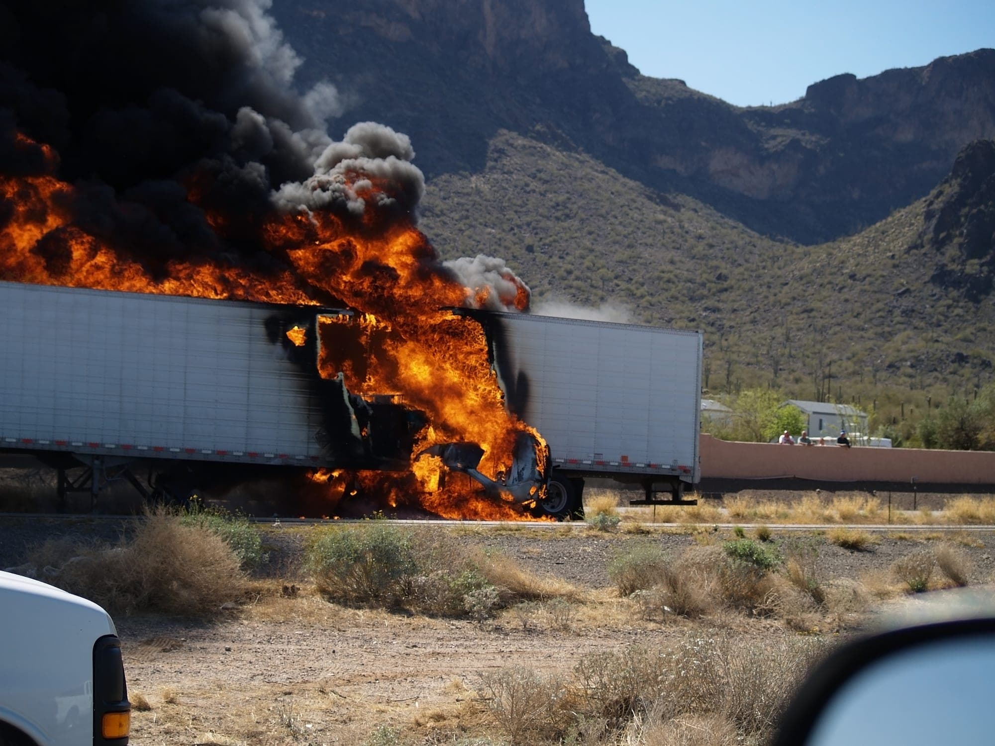 Semi-trailer engulfed in flames along a desert highway