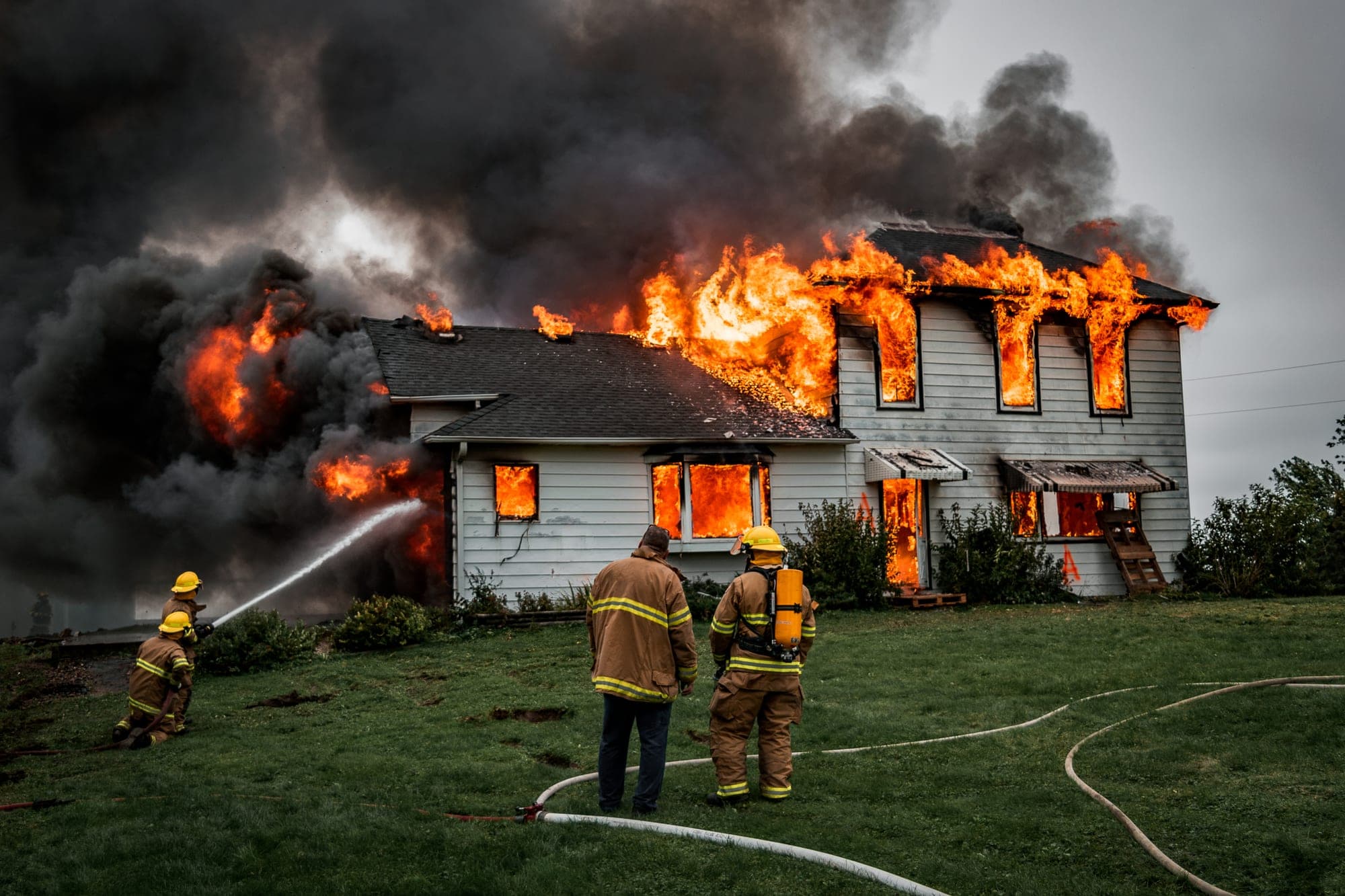 Firefighters hosing down a burning two-story house